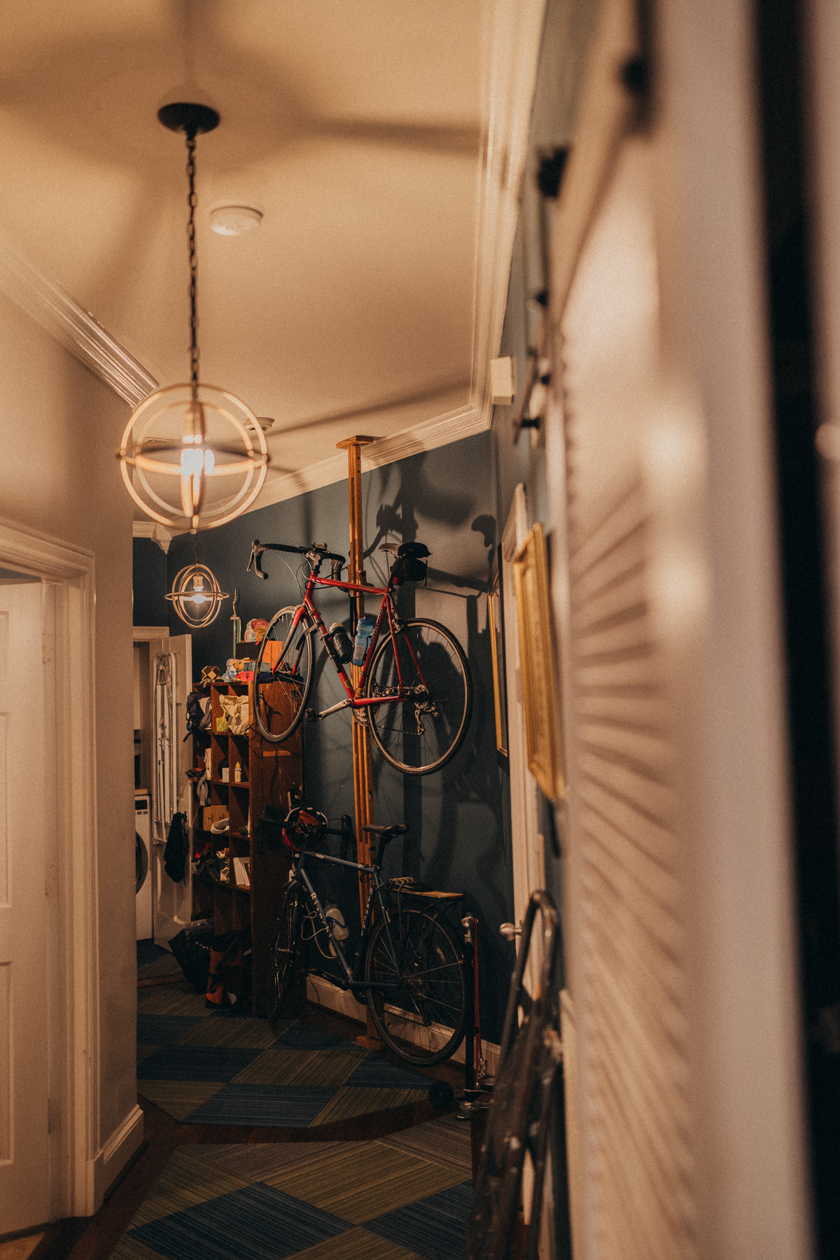 Two bicycles stored vertically in the warm light of the temporary home